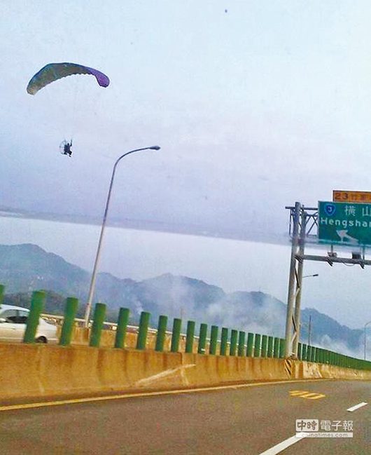 新竹縣台68快速道路竹東段，昨被網友目擊一台飛行傘低空飛過道路旁，險象環生。（徐養齡翻攝）