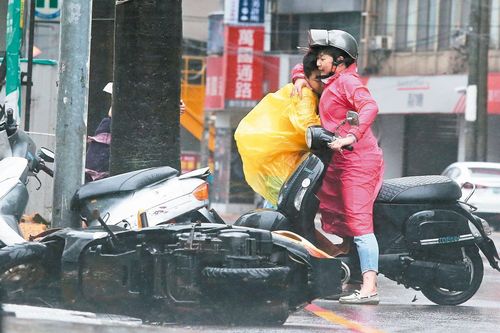 台中地区9月27日风势强劲，一位骑摩托车的妇人受到“风阻”，与亲人紧拥在一起。 台湾《联合报》记者黄仲裕／摄影