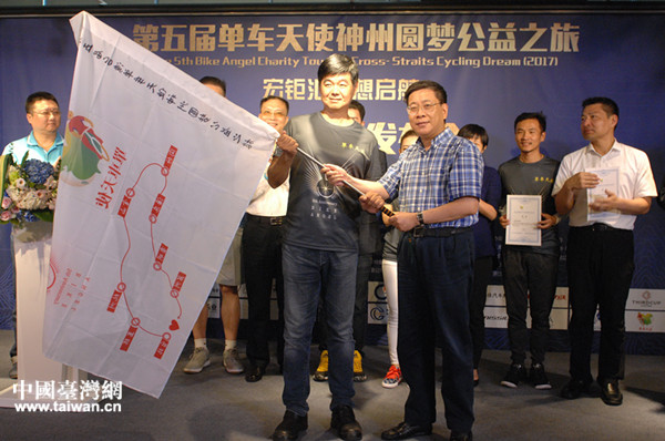 上海市台办主任李文辉（右）向“单车天使”授旗并宣布上海站骑行开始