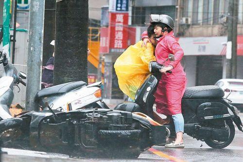台中地区9月27日风势强劲,一位骑摩托车的妇人受到“风阻”,与亲人紧拥在一起。 台湾《联合报》记者黄仲裕/摄影